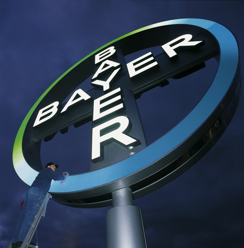 Foto von einer Putzkraft, die das Logo des Bayer Konzerns reinigt