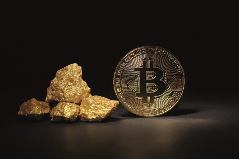 Auf dem Bild ist ein Stück Gold und eine symbolische Bitcoin-Münze abgebildet.
