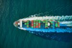 Ein Containerschiff auf dem Meer aus der Vogelperspektive.